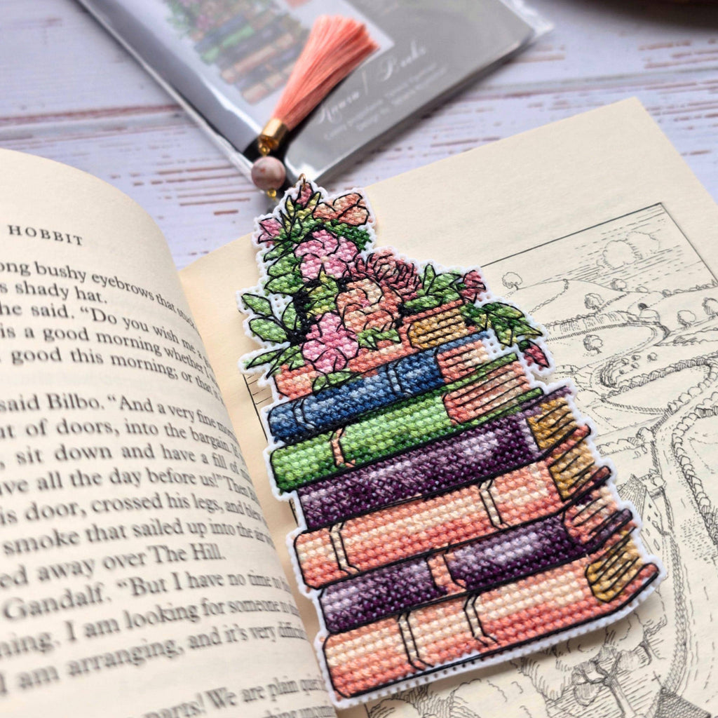 Cross Stitch Bookmark Kit on Plastic Canvas displayed on an open book with decorative tassel and floral design.