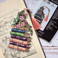 Cross Stitch Bookmark Kit on Plastic Canvas featuring a stack of colorful books and floral design with tassel.