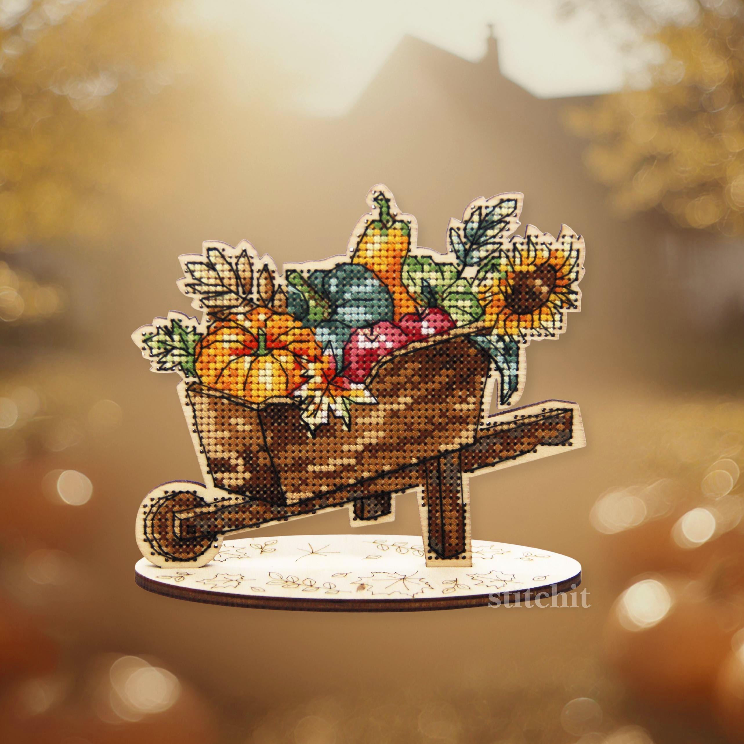 Harvest Cross Stitch Kit on Wood displayed as a colorful autumn decoration with fruits and sunflowers.