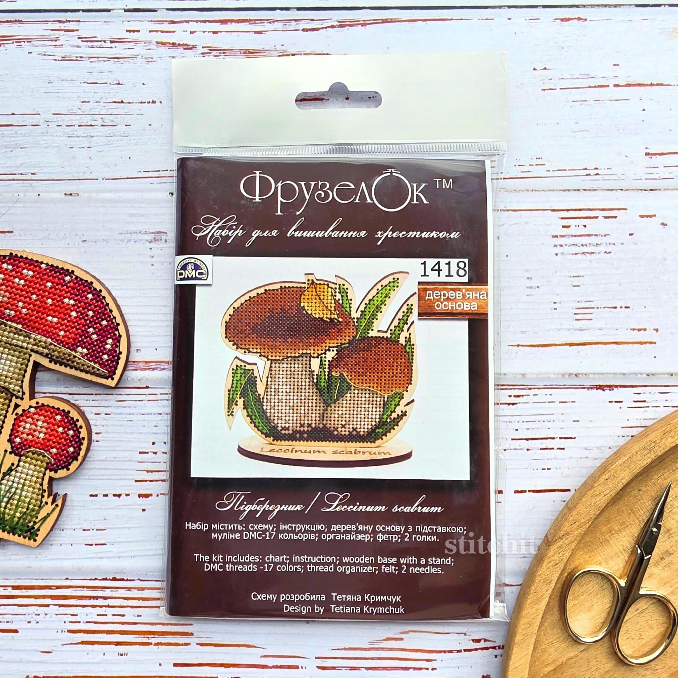 Forest Mushroom Cross Stitch Kit on Wood — Birch Bolete kit packaging beside two finished stitched mushrooms and scissors on a white wooden surface.Forest Mushroom Cross Stitch Kit on Wood — Birch Bolete kit packaging beside two finished stitched mushrooms and scissors on a white wooden surface