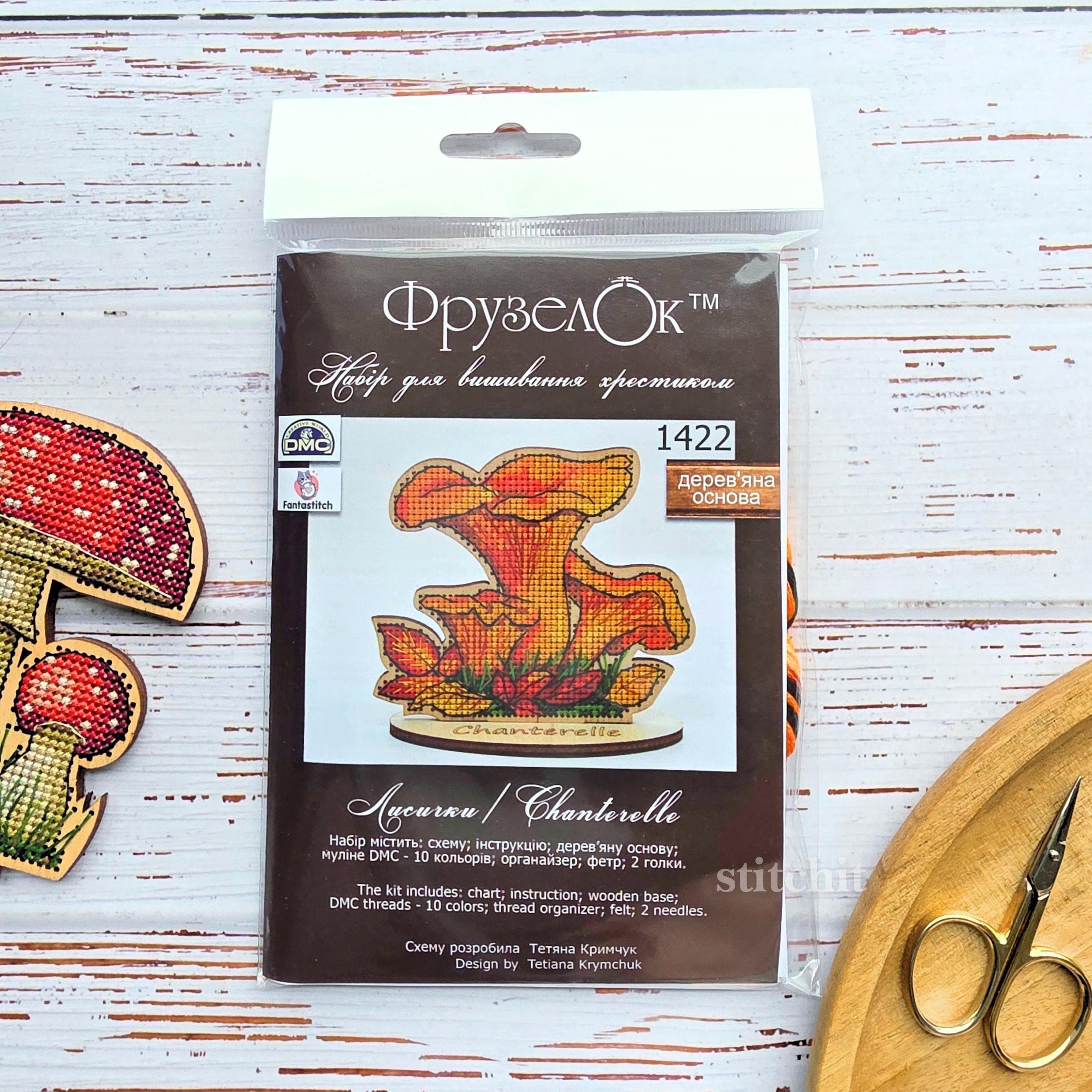 Chanterelle Cross Stitch Kit on Wood — kit packaging with chart beside two finished embroidered mushrooms and scissors on a white surface.