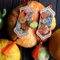 Pumpkin Cross Stitch Kit on Wood showcasing vibrant pumpkin designs with tassels surrounded by autumn gourds.