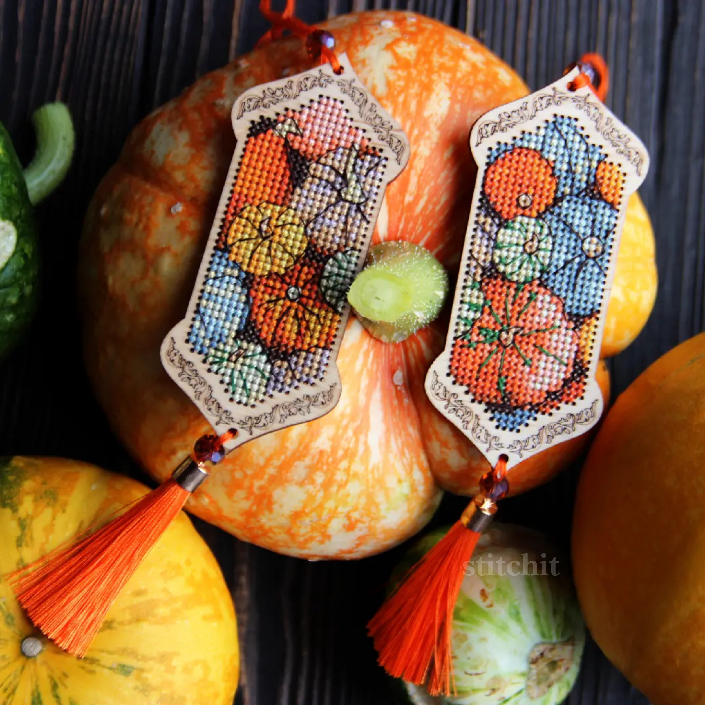 Pumpkin Cross Stitch Kit on Wood showcasing vibrant pumpkin designs with tassels surrounded by autumn gourds.